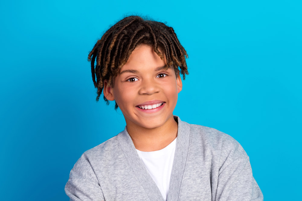 Young boy smiling on blue background | Dental sealants for kids