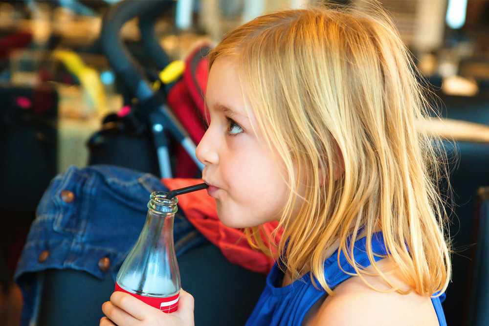 Young girl drinking a soft drink | Child's diet & dental health