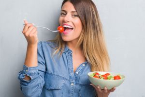 Smiling young woman eating salad | Diet Tips for Orthodontic Success